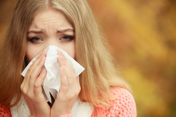 Sick ill woman in autumn park sneezing in tissue. — Stock Photo, Image