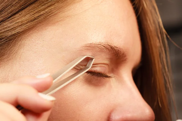 Woman tweezing eyebrows depilating with tweezers — Stock Photo, Image