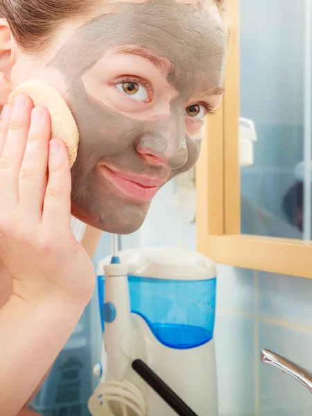 Mulher removendo máscara de barro facial lama no banheiro — Fotografia de Stock