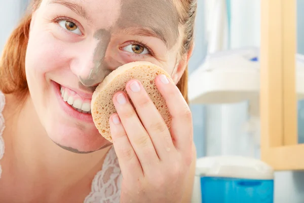 Woman removing facial clay mud mask in bathroom — Stock Photo, Image