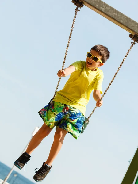 Pojken spelar svängande av swing-set. — Stockfoto