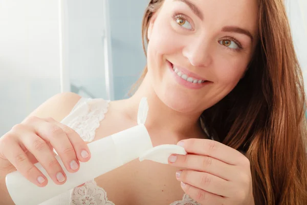 Woman removing makeup with cotton swab pad.