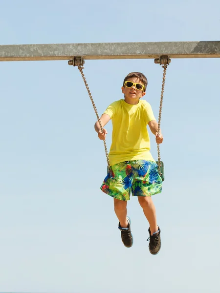 Ragazzo che gioca oscillando da swing-set. — Foto Stock