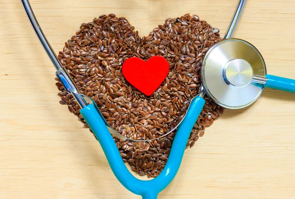 Raw flax seeds heart shaped and stethoscope — Stock Photo, Image