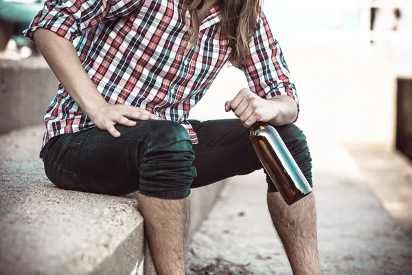 Man depressed with wine bottle sitting on beach outdoor — Stock Photo, Image