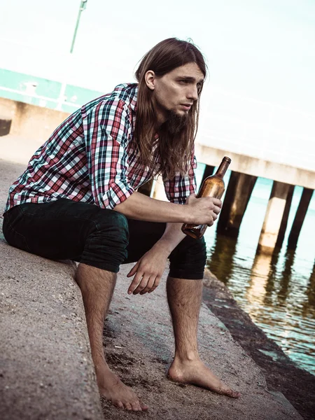 Hombre deprimido con botella de vino sentado en la playa al aire libre — Foto de Stock