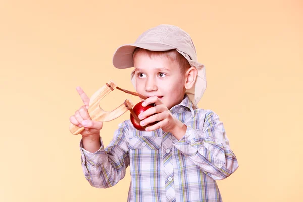 Ung pojke använda sling skott skjuta apple. — Stockfoto