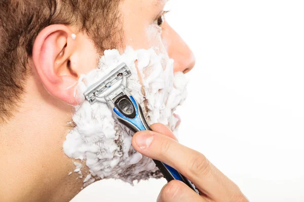 Mann rasiert sich mit Rasiermesser mit Sahneschaum. — Stockfoto