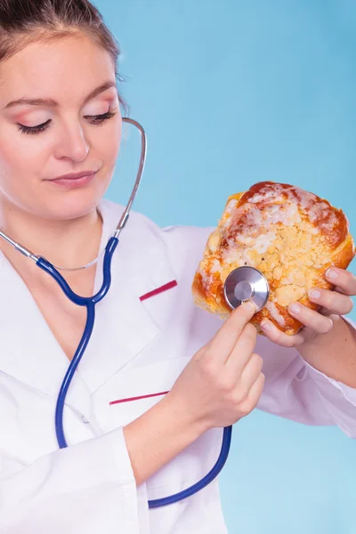 Diététiste examiner petit pain sucré avec stéthoscope . — Photo