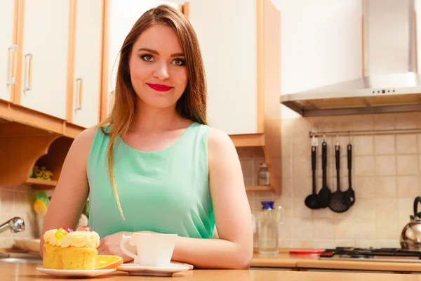 Woman with coffee and cake in kitchen. Gluttony. — Stock Photo, Image