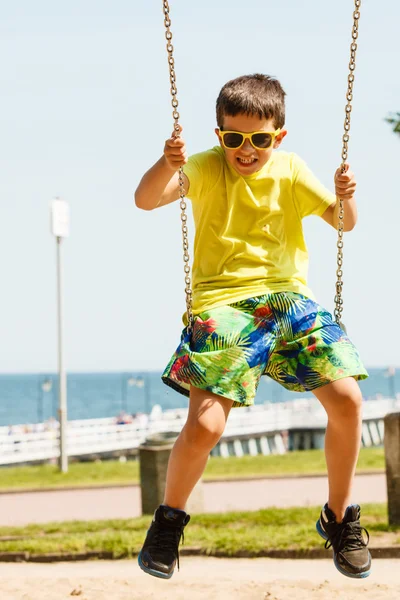 Pojken spelar svängande av swing-set. — Stockfoto