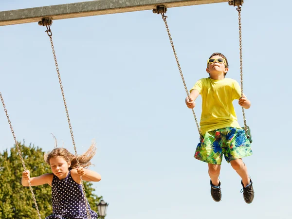 Swingset で楽しい 2 人の子供. — ストック写真