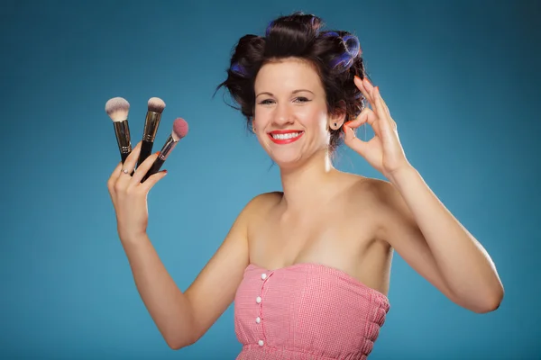 Woman in hair rollers holds makeup brushes — Stock Photo, Image