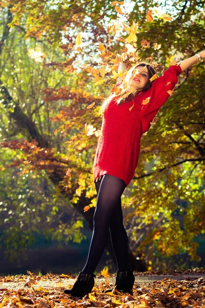 Jovem mulher jogando folhas . — Fotografia de Stock