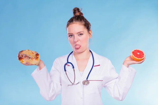 Disgusted dietitian with sweet bun and grapefruit. — Stock Photo, Image