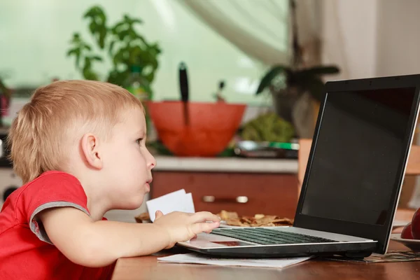 Bambino con computer portatile sul tavolo in casa . — Foto Stock