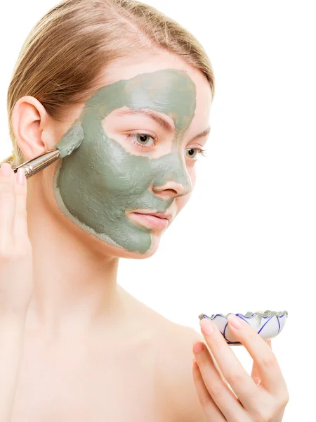 Chica aplicando mascarilla de arcilla facial en su cara — Foto de Stock