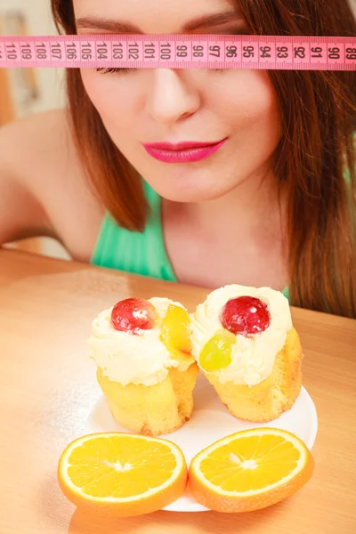 Femme avec ruban à mesurer et gâteau. Dilemme alimentaire . — Photo