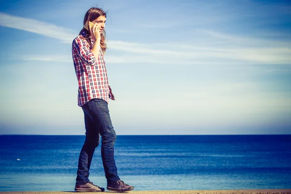 Homem à beira-mar recebendo uma chamada em seu telefone — Fotografia de Stock