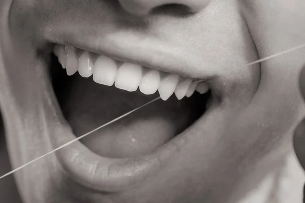 Młody człowiek czyszczenia jej białe zęby z nici dentystyczne — Zdjęcie stockowe