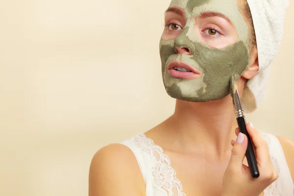 Vrouw met borstel klei modder masker toepassen op haar gezicht — Stockfoto