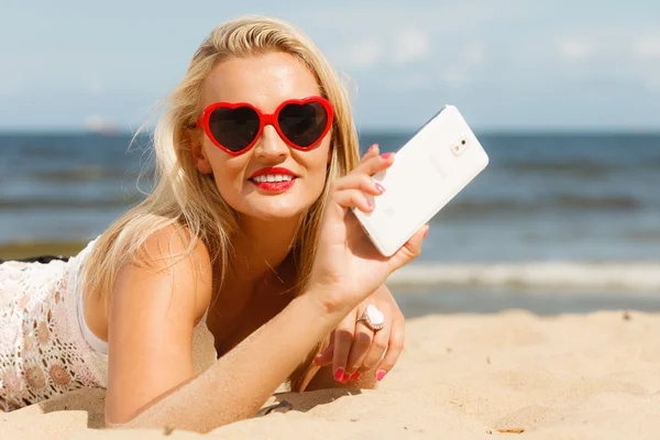Mujer acostada en la playa de arena usando el teléfono celular —  Fotos de Stock