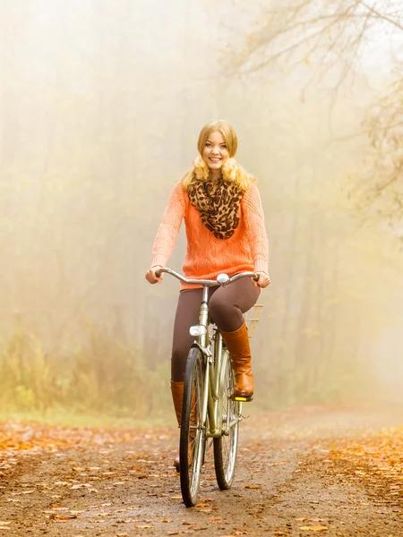 Active woman riding bike in autumn park. — Stock Photo, Image