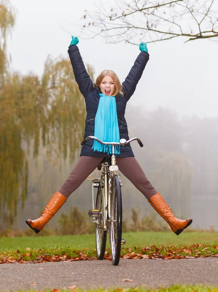 Mujer activa que se divierte montando bicicleta en el parque de otoño — Foto de Stock