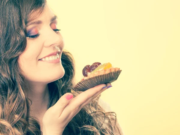 Frau hält Kuchen mit geschlossenen Augen in der Hand — Stockfoto