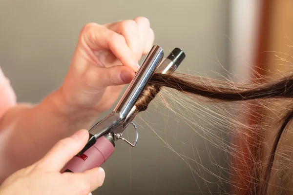 Estilista rizando el pelo para mujer joven. — Foto de Stock