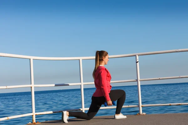 Woman doing sports exercises outdoors by seaside — Stock Photo, Image