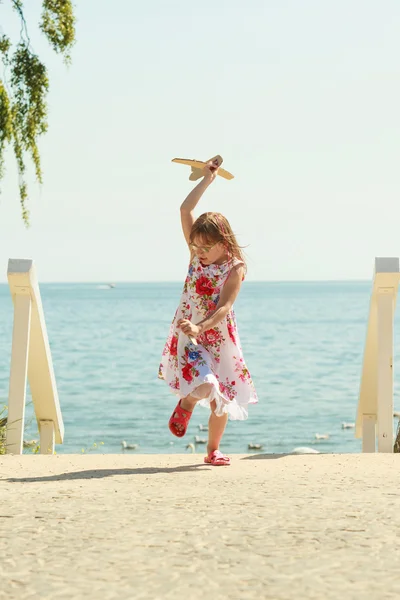 Klein meisje kind op strand met papier vliegtuig vliegtuig — Stockfoto