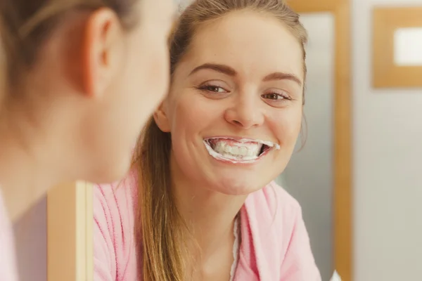 Mulher escovando os dentes de limpeza no banheiro — Fotografia de Stock