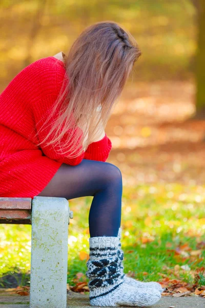 Sorglig kvinna sitter på bänk i parken — Stockfoto