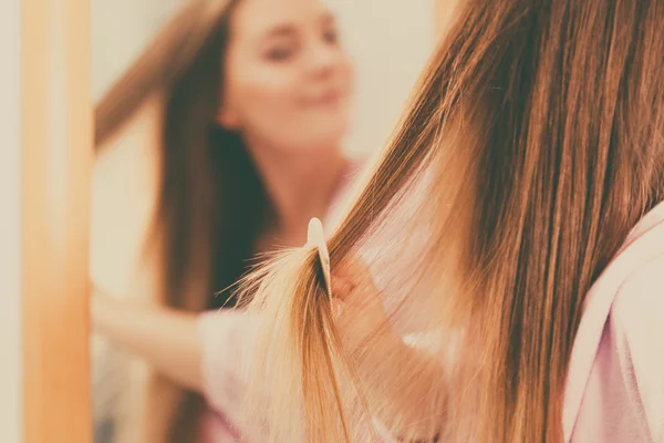 Mujer peinando su pelo largo en el baño — Foto de Stock