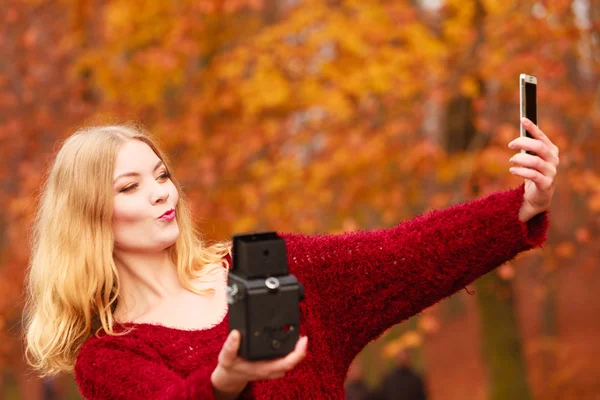 Женщина с камерой и смартфоном делает селфи — стоковое фото