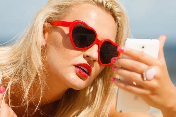 Woman lying on sandy beach using cell phone — Stock Photo, Image