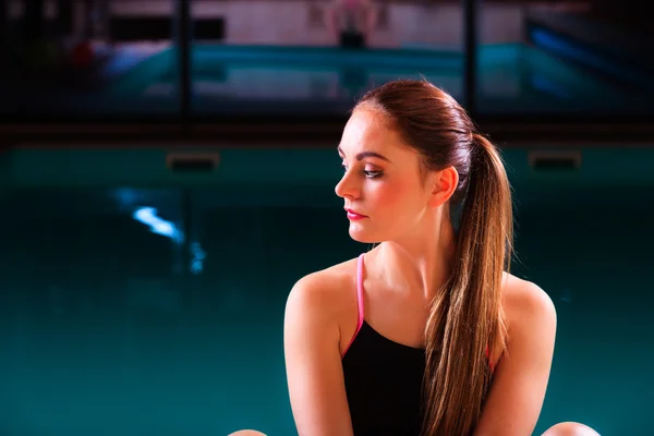 Mujer deportiva en el borde de la piscina junto a la piscina . — Foto de Stock