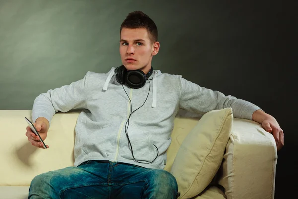 Hombre en el sofá con auriculares smartphone —  Fotos de Stock