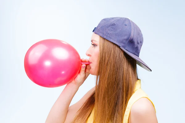 Vrouwelijke tiener oppompen rode ballon. — Stockfoto