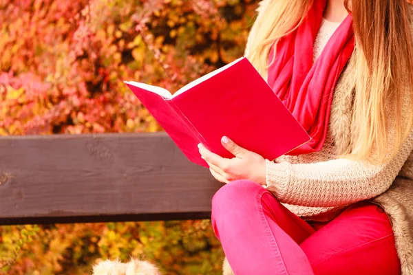 Женщина отдыхает в осеннем парке, читая книгу — стоковое фото