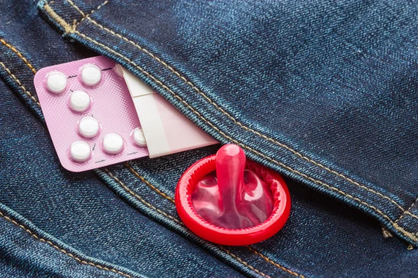 Pills and condom in denim pocket. — Stock Photo, Image