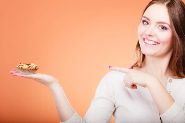 Усміхнена жінка тримає торт в руці вказуючи пальцем — стокове фото