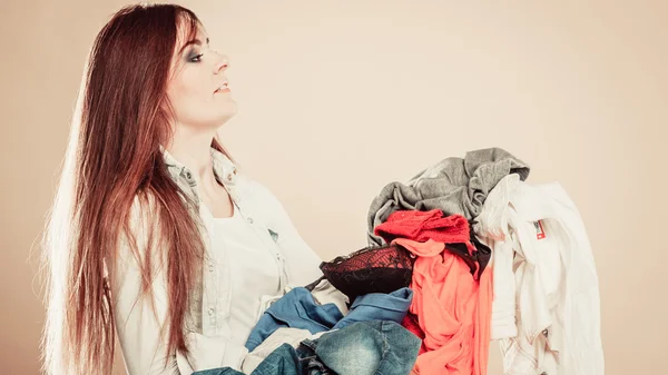Boční pohled mladá žena drží hromadu oblečení. — Stock fotografie
