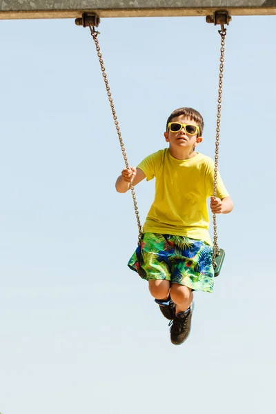 Pojken spelar svängande av swing-set. — Stockfoto