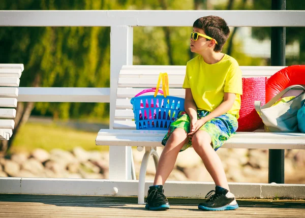 Ragazzo seduto sulla panchina con giocattoli . — Foto Stock
