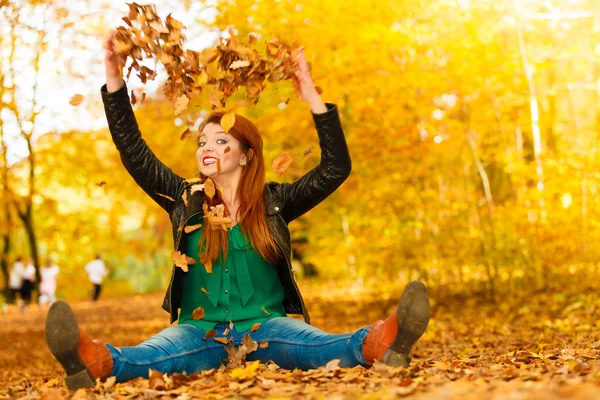 Dziewczyna relaks w jesiennym parku rzucanie liści w górę w powietrzu. — Zdjęcie stockowe