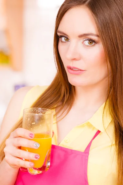 Kobieta w kuchni picie świeżego soku pomarańczowego — Zdjęcie stockowe