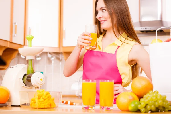 Mulher na cozinha beber suco de laranja fresco — Fotografia de Stock