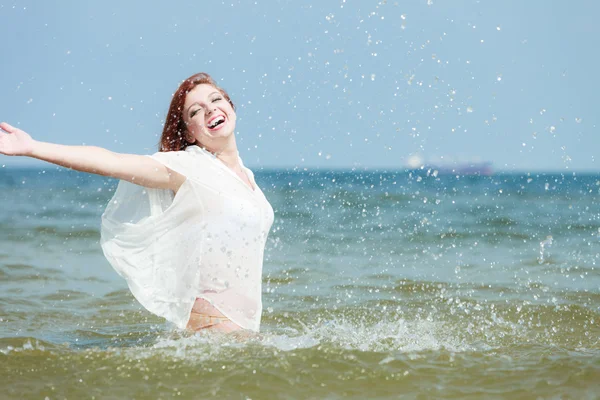 Chica salpicando agua en la costa. — Foto de Stock